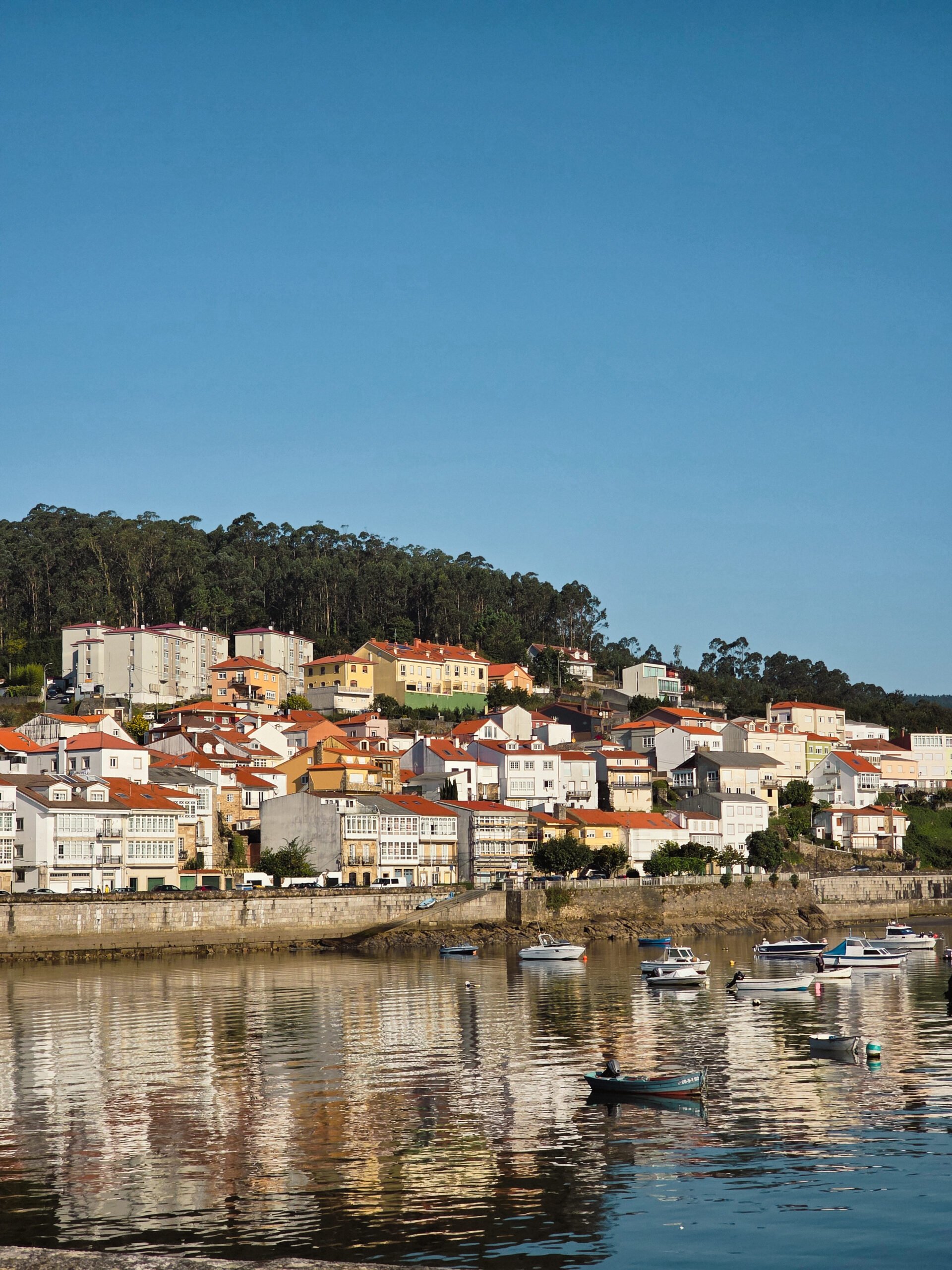 corcubion-vista-mar-costa-da-morte Vista panorâmica da vila de Corcubión, na Costa da Morte, com o mar e as casas coloridas à beira da baía.