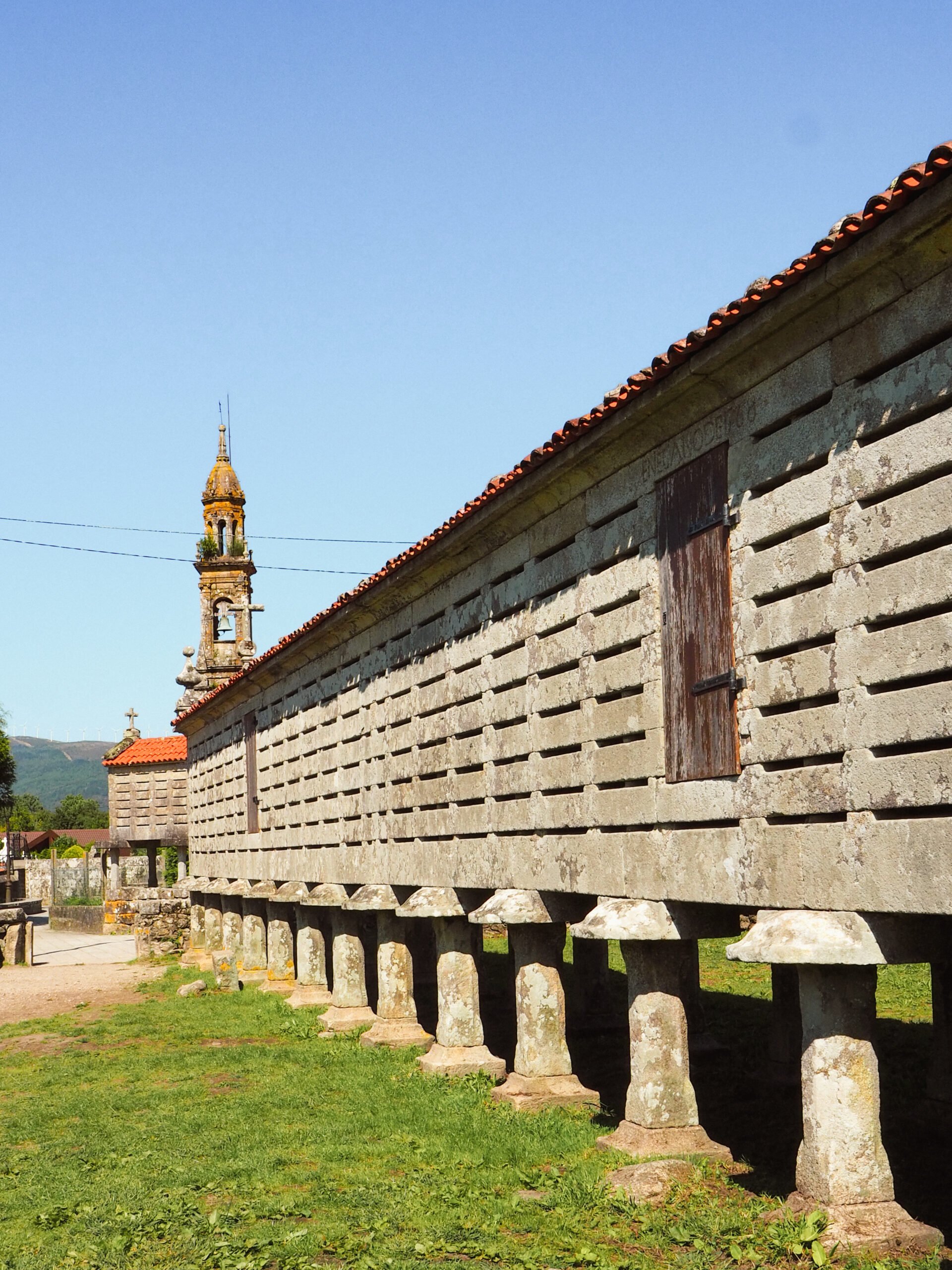 Vista geral do hórreo de Carnota, uma das construções mais emblemáticas da Galiza, rodeado por paisagem rural.