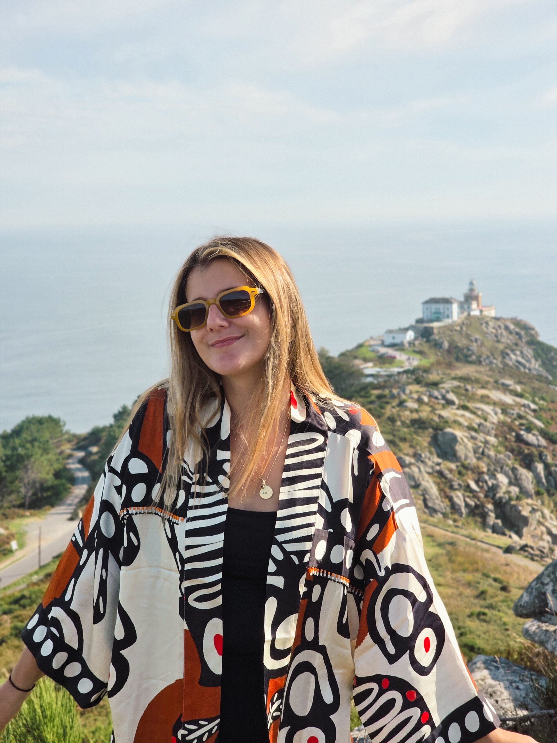 patricia-carvalho-monte-facho-farol-finisterra Patrícia Carvalho no topo do Monte Facho, com o Farol de Finisterra e o Atlântico ao fundo.