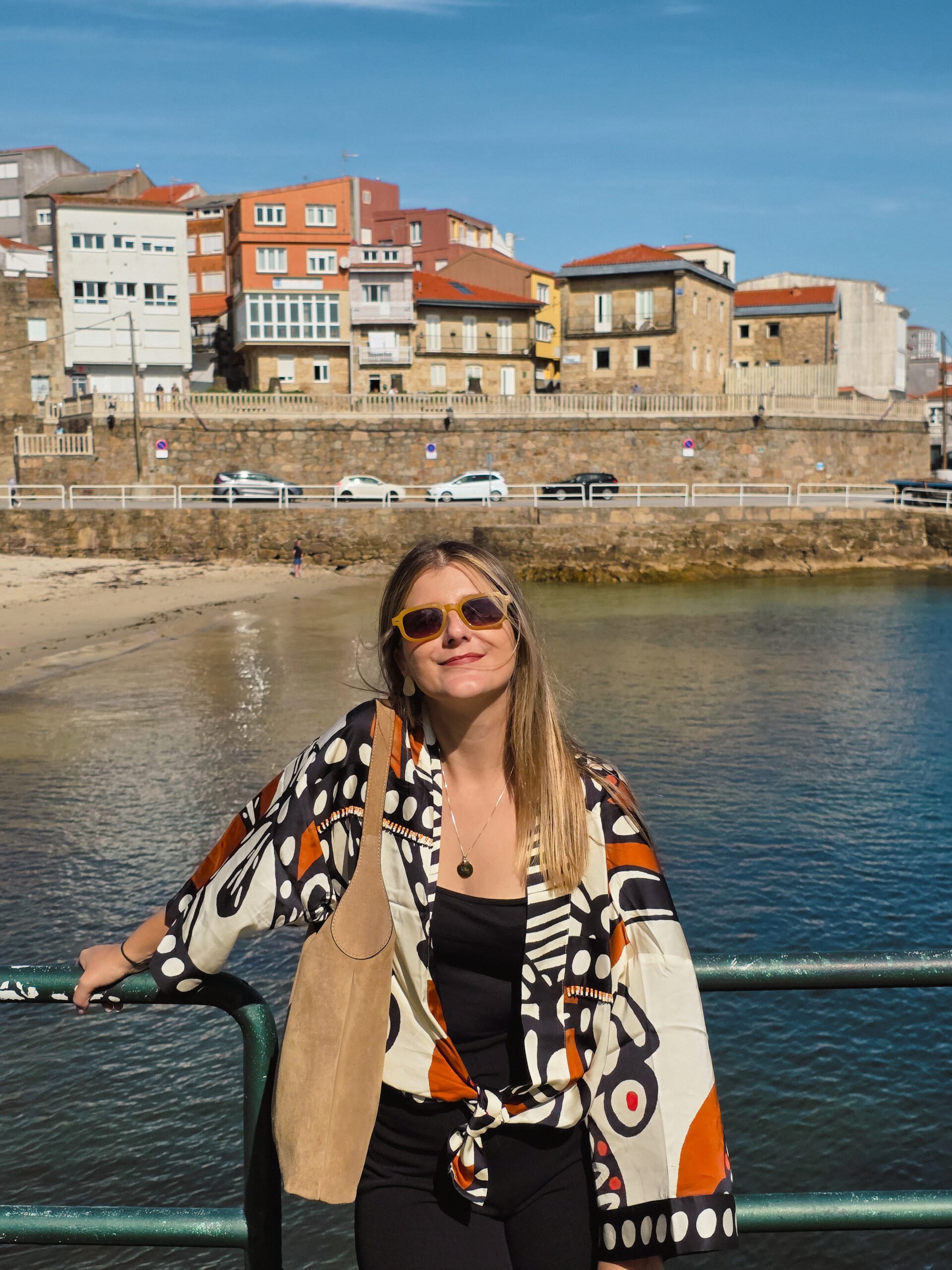 patricia-carvalho-praia-da-ribeira-finisterra Patrícia Carvalho na Praia da Ribeira, em Finisterra, com vista para o porto e o mar da Costa da Morte.