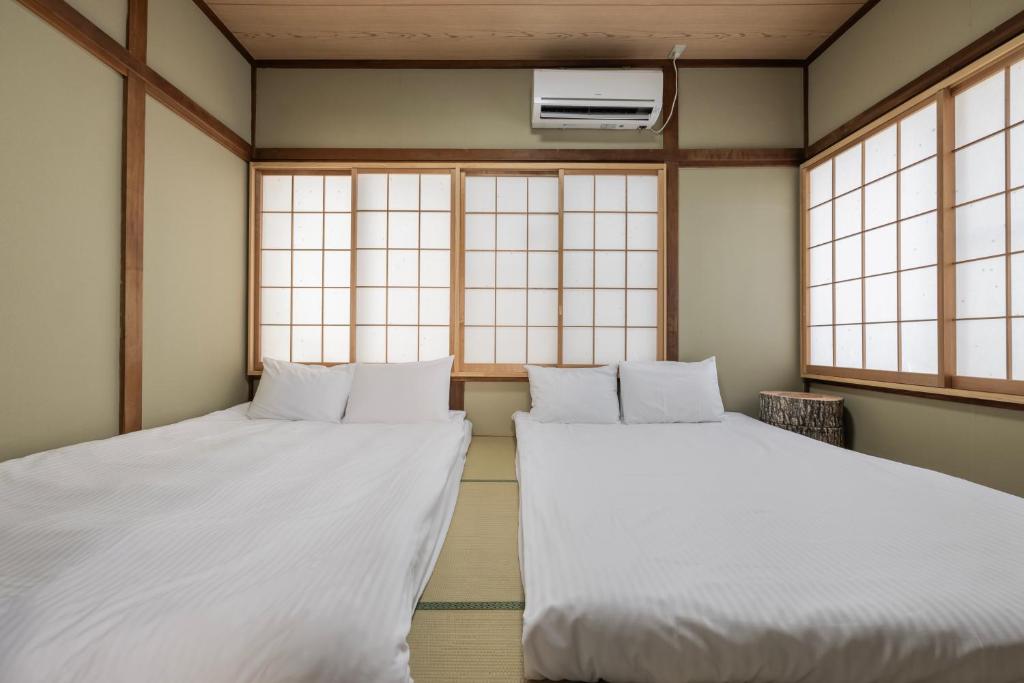 Quarto do apartamento Self Check-in Shinjuku Windhouse em Tóquio, com dois futons tradicionais lado a lado e janelas em estilo japonês.