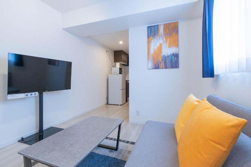Área de estar do Curasion Oyodonaka em Osaka, com sofá, televisão e acesso à kitchenette, ideal para viajantes que procuram alojamento prático em Osaka.