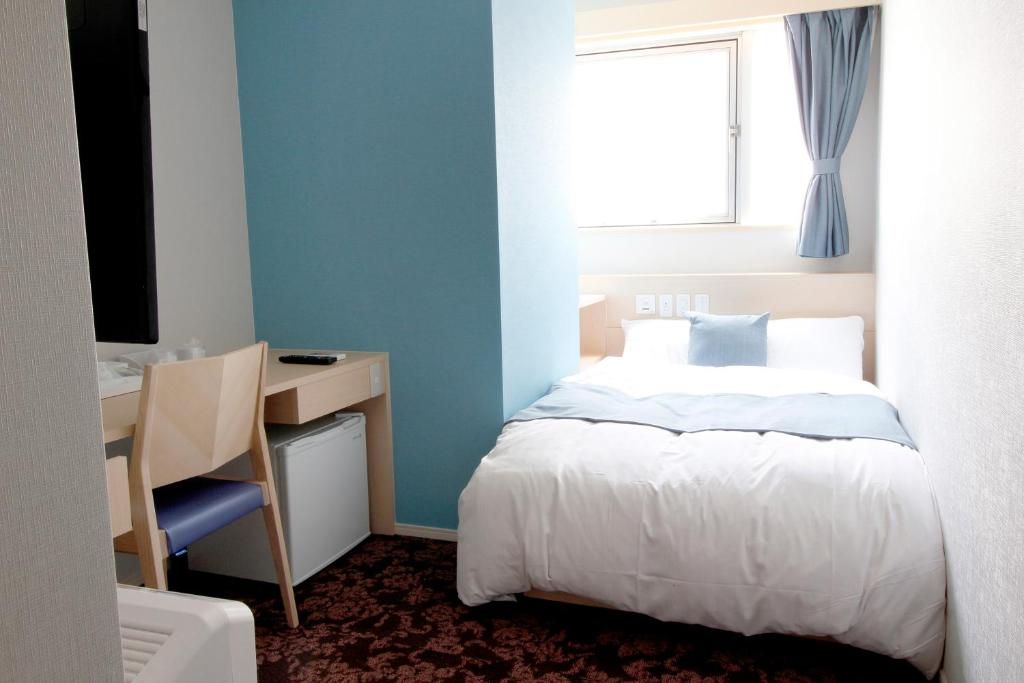 Quarto compacto e luminoso do Hotel M Matsumoto, com cama dupla, secretária e decoração simples.