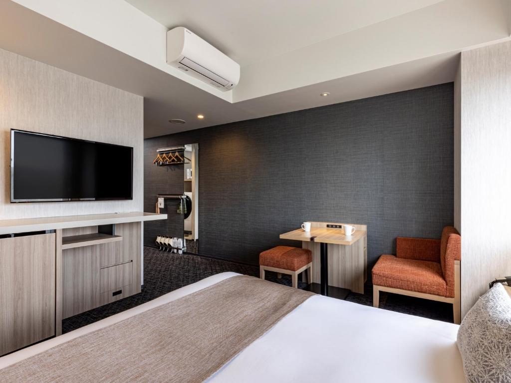 Interior do quarto no Tokyu Stay Kanazawa, com área de estar, televisão e espaço de arrumação, ideal para uma estadia prática na cidade.
